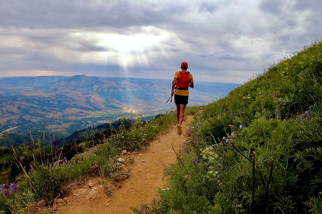 Trail runner with beautiful rays of sun coming through the cloud. Mike McKnight on Ben Lomond Trail overlooking Eden, Utah.