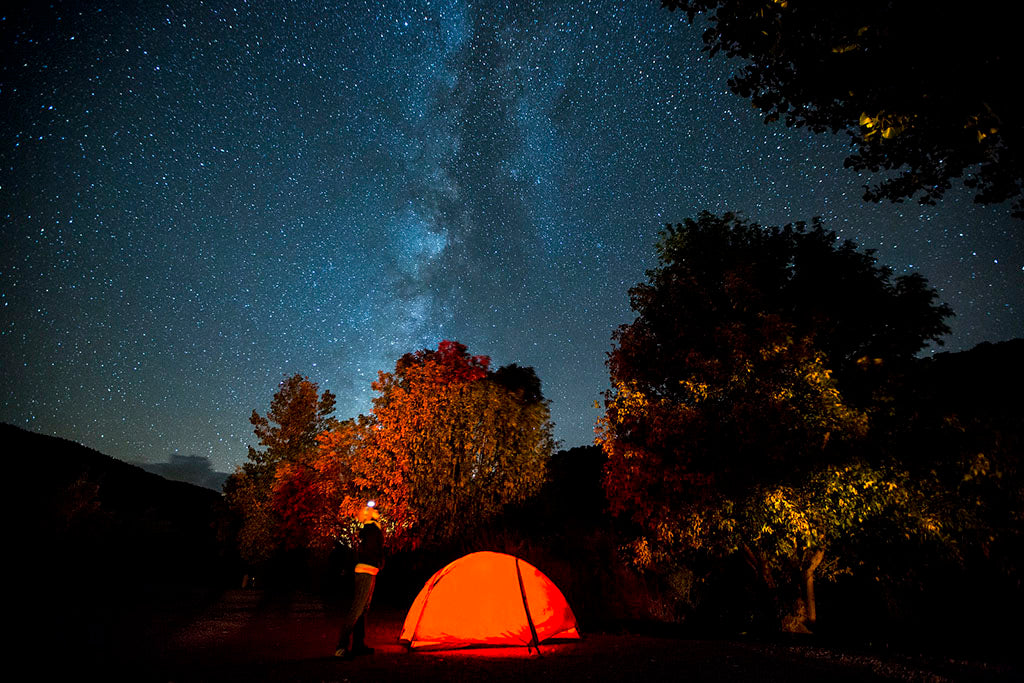 Night sky showing Milky Way galaxy with glowing red tent