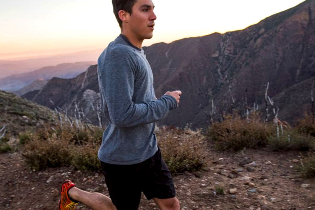male trail runner on trail overlooking mountain peaks