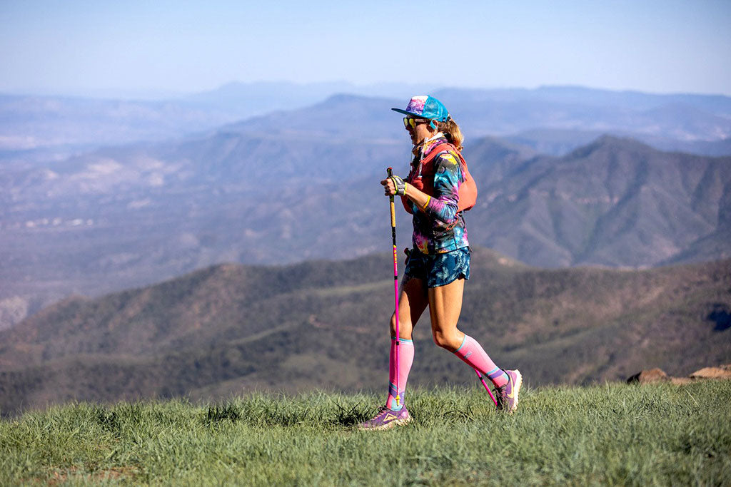 Trail runner Shelby Farrell running on trail overlooking scenic mountains.