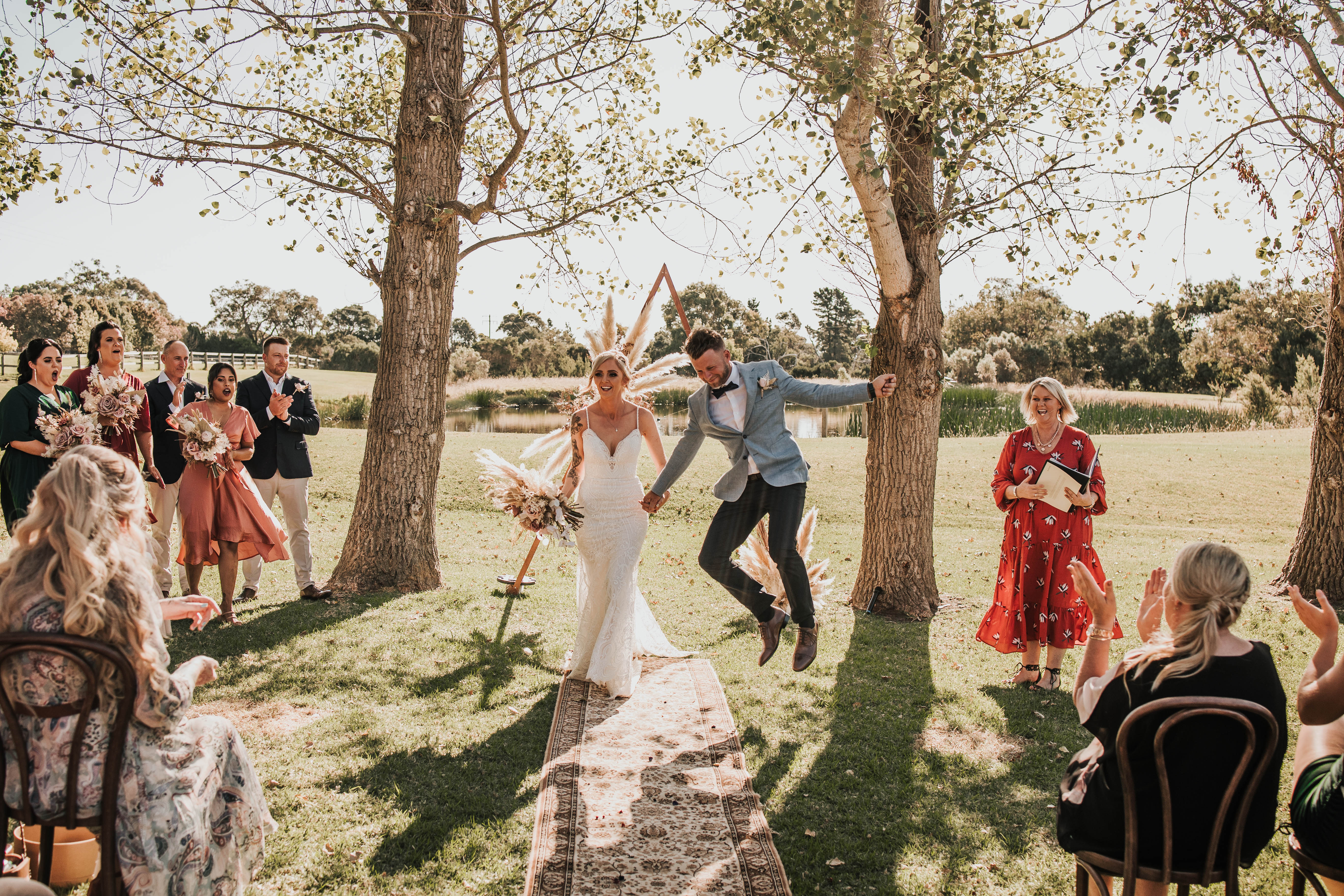 Groom Andrew jumps for joy as he holds hand with Bride Hayley, after the wedding ceremony