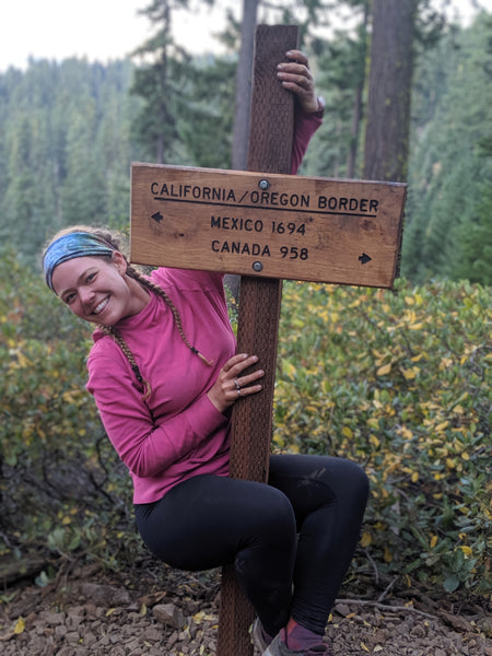 Kate hangs from California/Oregon border sign on the PCT