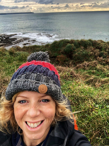 Gail smiling in a winter hat with the ocean in the background