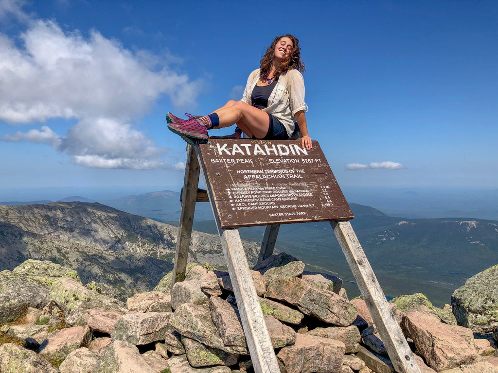 Woman sitting on Katahdin summit sign