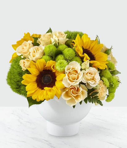 sunflowers, green pompons, light yellow or white spray roses, green fuji mums in a white ceramic container