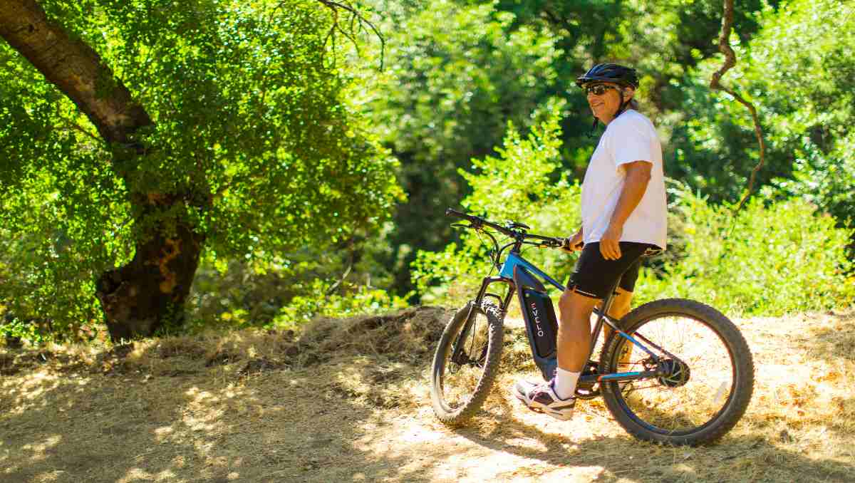 A man riding an electric bike in the forest.