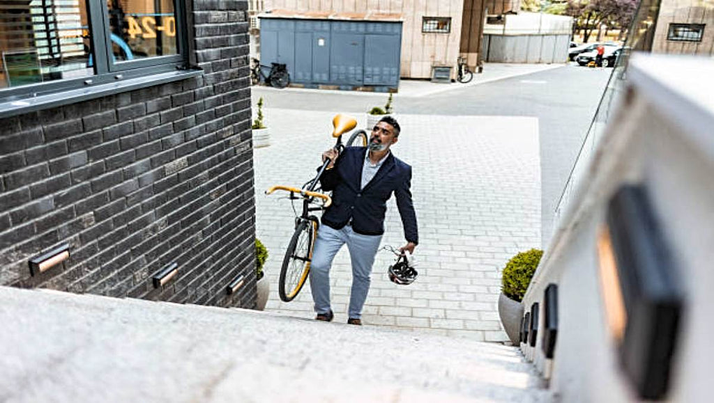 A man carrying his bike up the stairs.