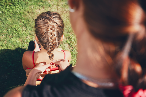 woman doing a french braid for a little girl