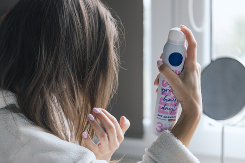 woman spraying dry shampoo on hair