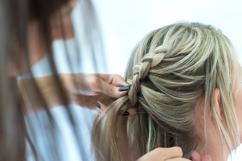 woman doing a waterfall braid on another woman's hair