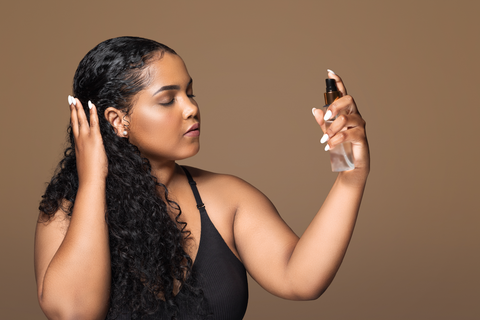 woman spraying hair perfume on hair