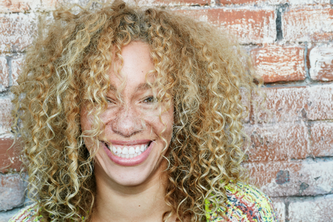 women with blonde curls smiling wide
