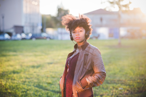 woman with curly hair on jog with headphones and hand in pocket