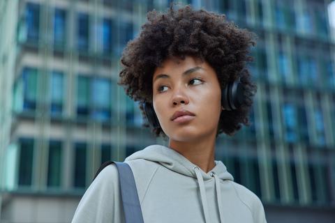 woman with short curls and grey sweatshirt with headphones