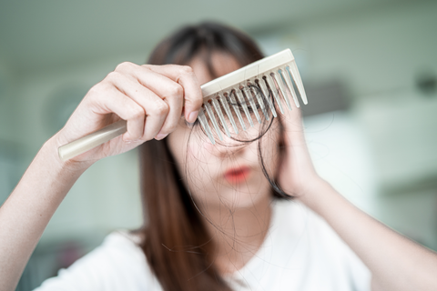 woman holding comb with fallen hair