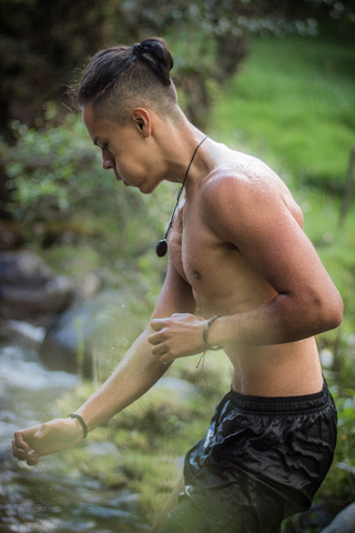 handsome man with long hair tied up working out outdoors