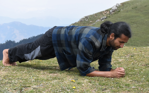 man with ponytail doing a plank outdoors