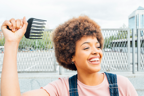 happy black woman with comb in hand