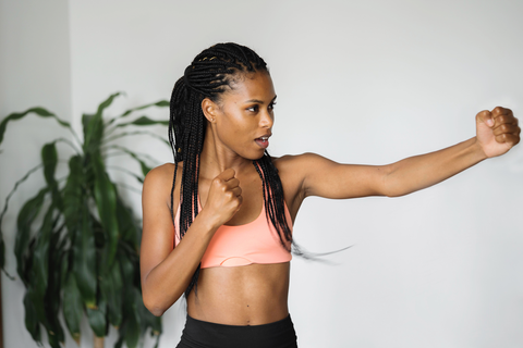 woman with braids and workout clothes making punching motion