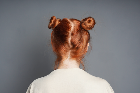backview of a woman's red hair head with space buns