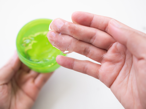 woman taking out a scoop of aloe vera gel in fingers