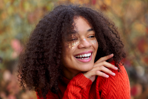 woman outdoors resting chin on hand with curly thick hair