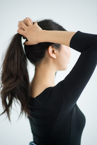 woman putting hair up in ponytail