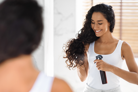 woman putting hair product in curly hair