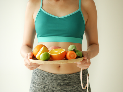 woman holding tray of healthy fruits and vegetables