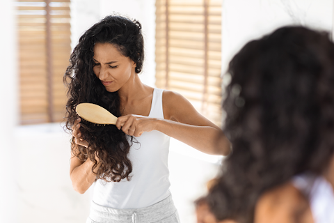 woman brushing her hair by looking in mirror