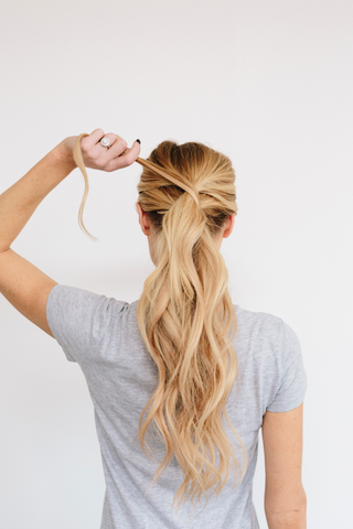 woman wrapping strand of hair around ponytail
