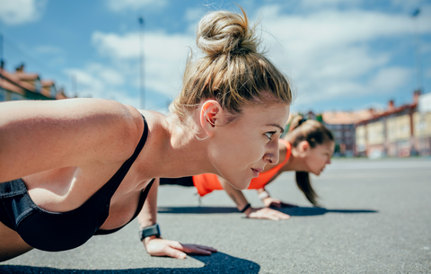 active woman with top bun doing a pushup