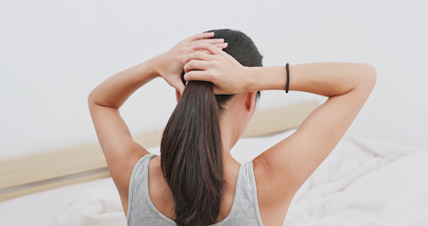 A lady tying her hair into a pony with her hairband round her wrist