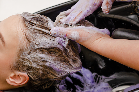 A lady having her hair washed with purple shampoo