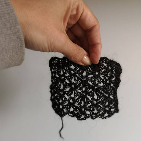 a hand holds a small lace swatch