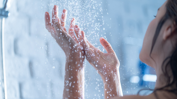 A woman holds her hands under the water to feel shower pressure