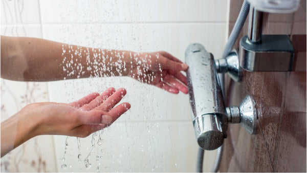 a woman holds her hands under the water while adjusting shower pressure