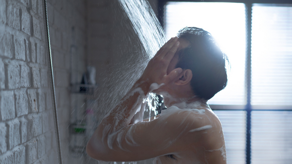 a man takes a shower after installing an adjustable shower arm extender