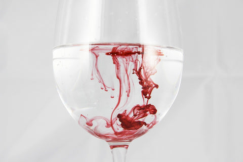 wine glass with water and red droplets