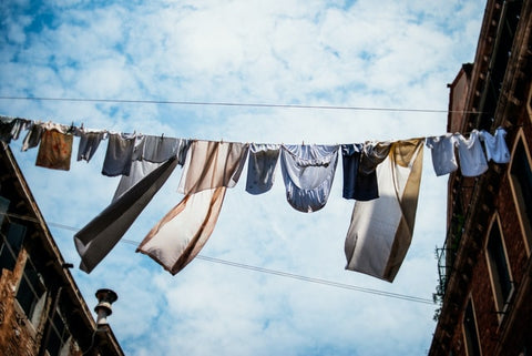 Variety of clothes air drying on a rope with a cloudy sky in the background 