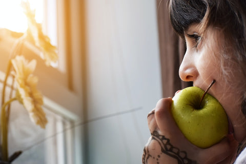 woman biting into a green apple