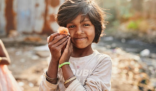 A young girl holds up a baby chick for the camera.