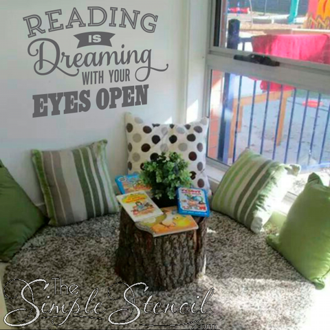 A vinyl wall decal in a classroom reading nook that reads "Reading is dreaming with your eyes open." The decal is surrounded by books and pillows, creating a cozy and inviting space for students to read.  This decal is a reminder to students that reading is a way to escape into different worlds and experience new things. It is a way to dream big and explore their imaginations.  This decal would be a great addition to any classroom reading nook. It is a reminder to students that reading is a fun and rewarding activity.