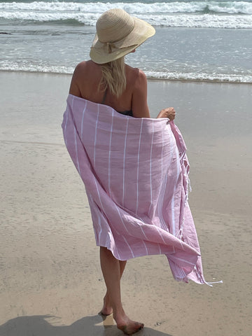 blond woman on beach wearing a pink turkish towel