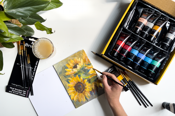 Finished painting of sunflowers with acrylics and paintbrush in artist's hand.