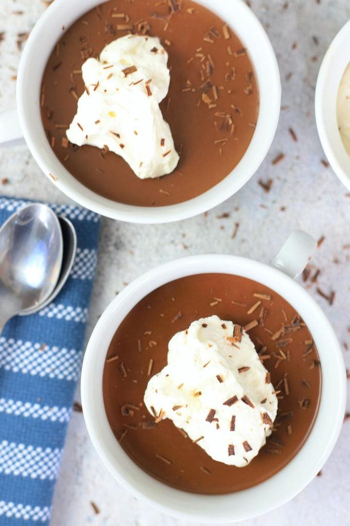 2 bowls of chocolate mousse topped with whipping cream