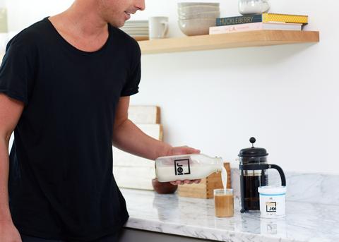 male pouring coffee into glass in kitchen
