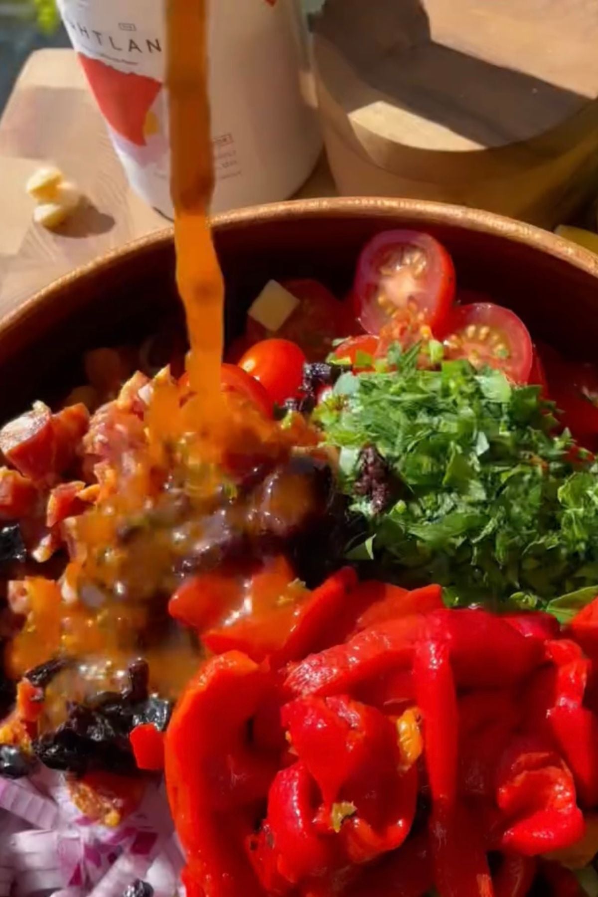 pouring dressing into the italian pasta salad.