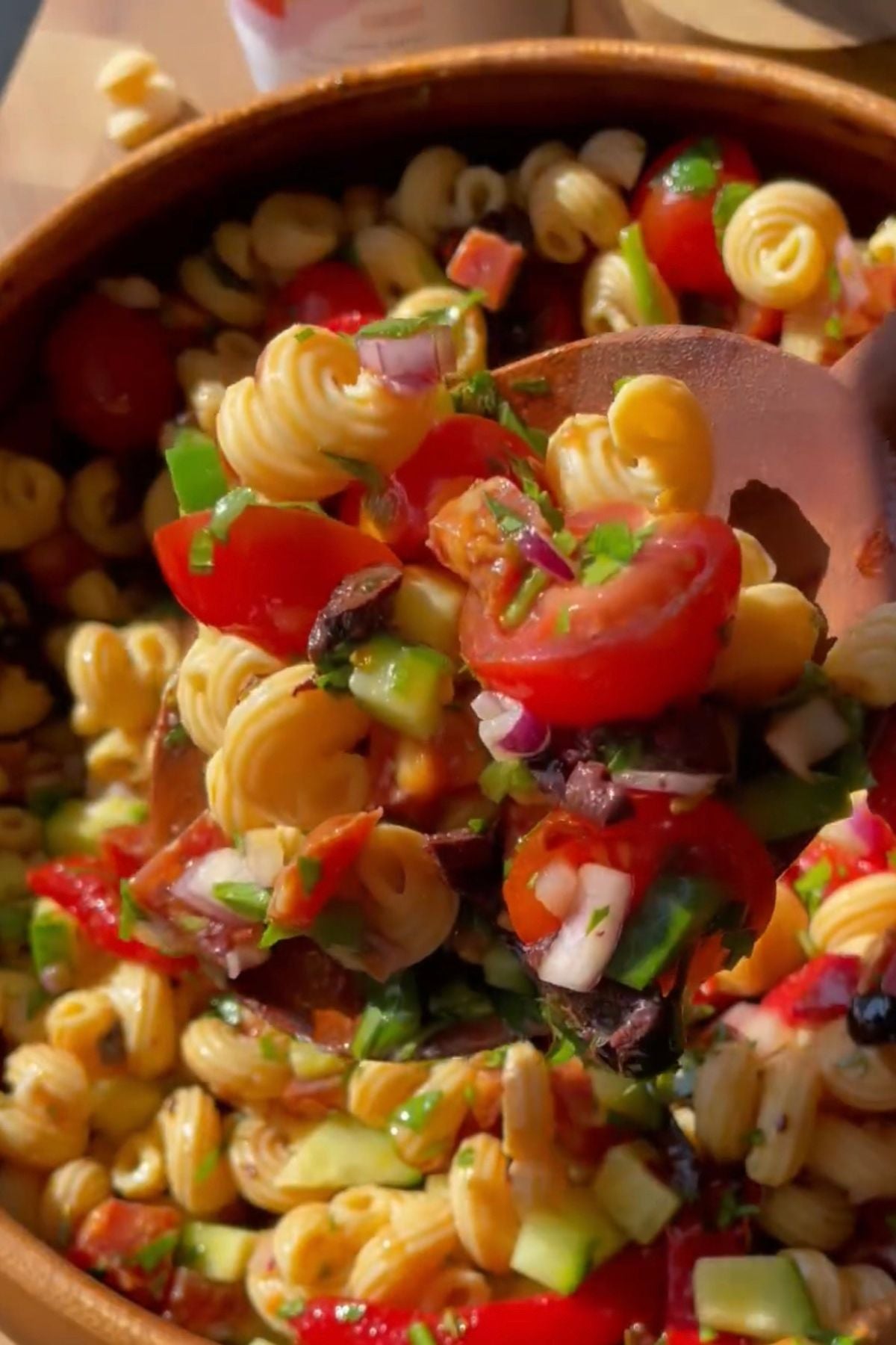 bowl of italian pasta salad and a wooden spoon.