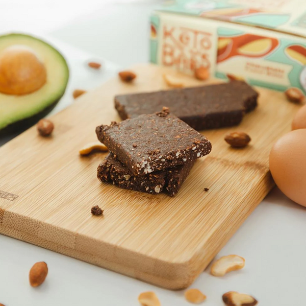 keto bars on a cutting board next to a half avocado.